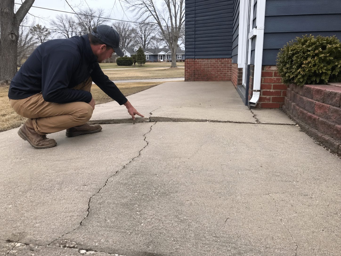 Concrete contractor inspecting and diagnosing failing concrete — repair vs replacement assessment