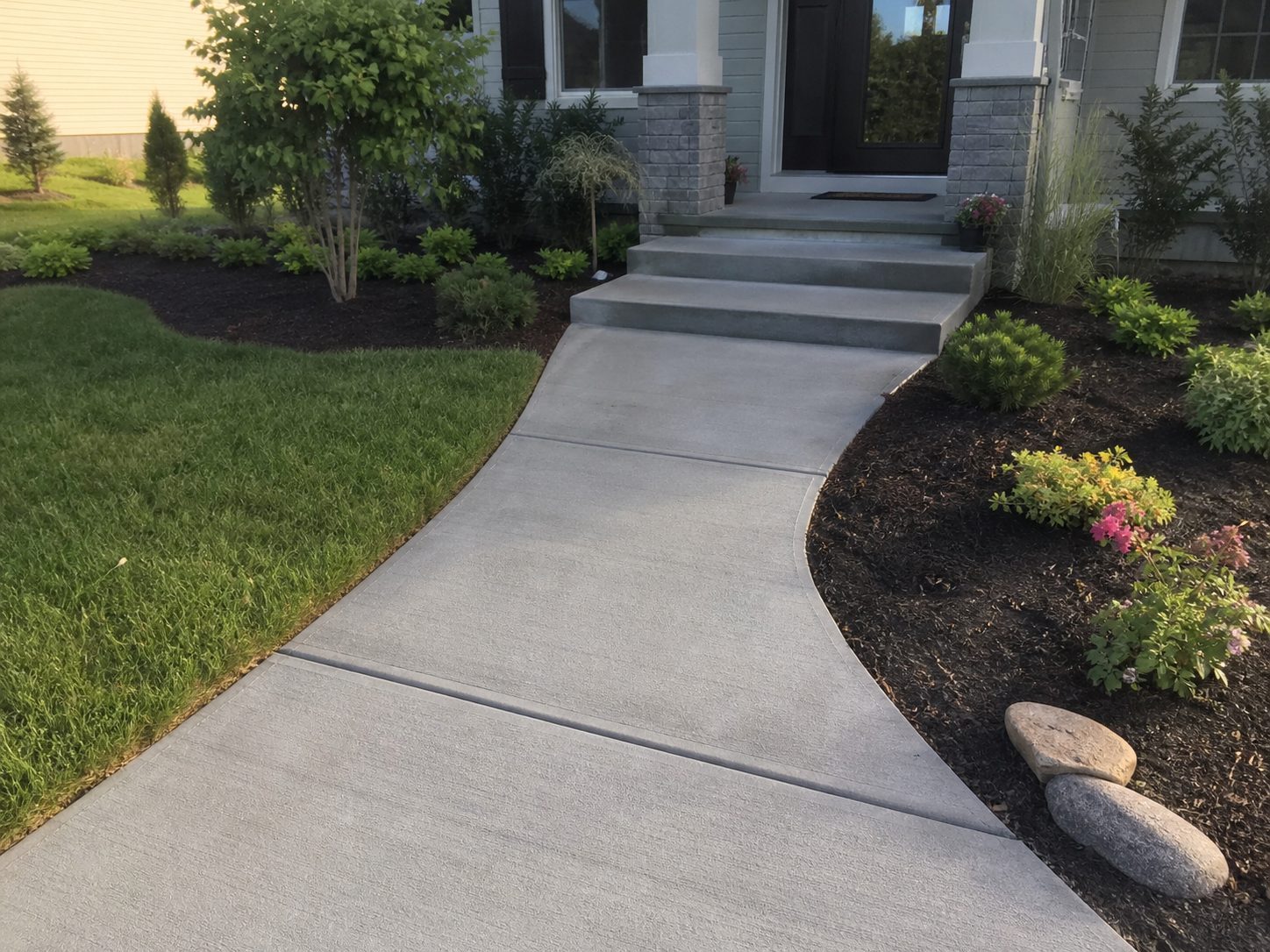 Finished concrete front walkway with steps and lush landscaping at a Lee's Summit, MO residence