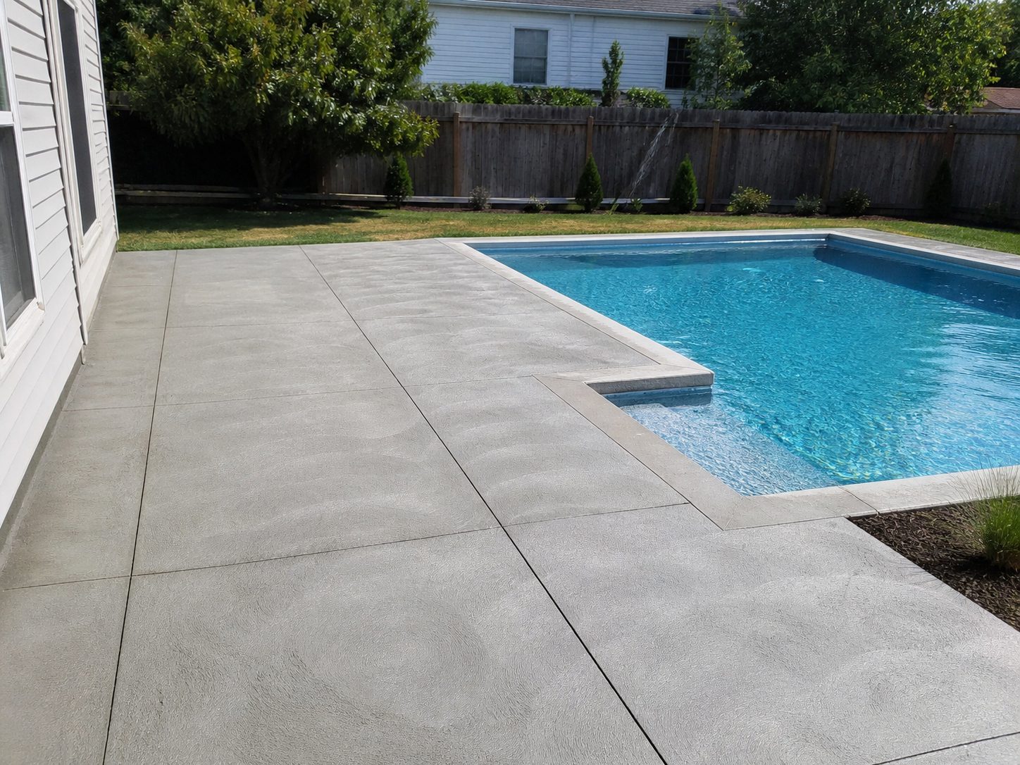 Clean broom-finish concrete pool deck surrounding a residential pool